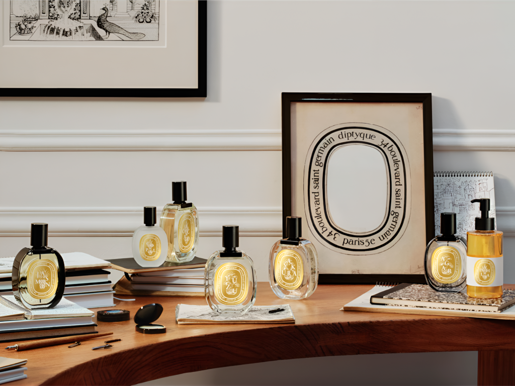 Mise en scène bureau de la gamme complète de parfums Diptyque édition limitée Voyage, avec les étiquettes de chaque pays posés parmi des livres et cadres photos
